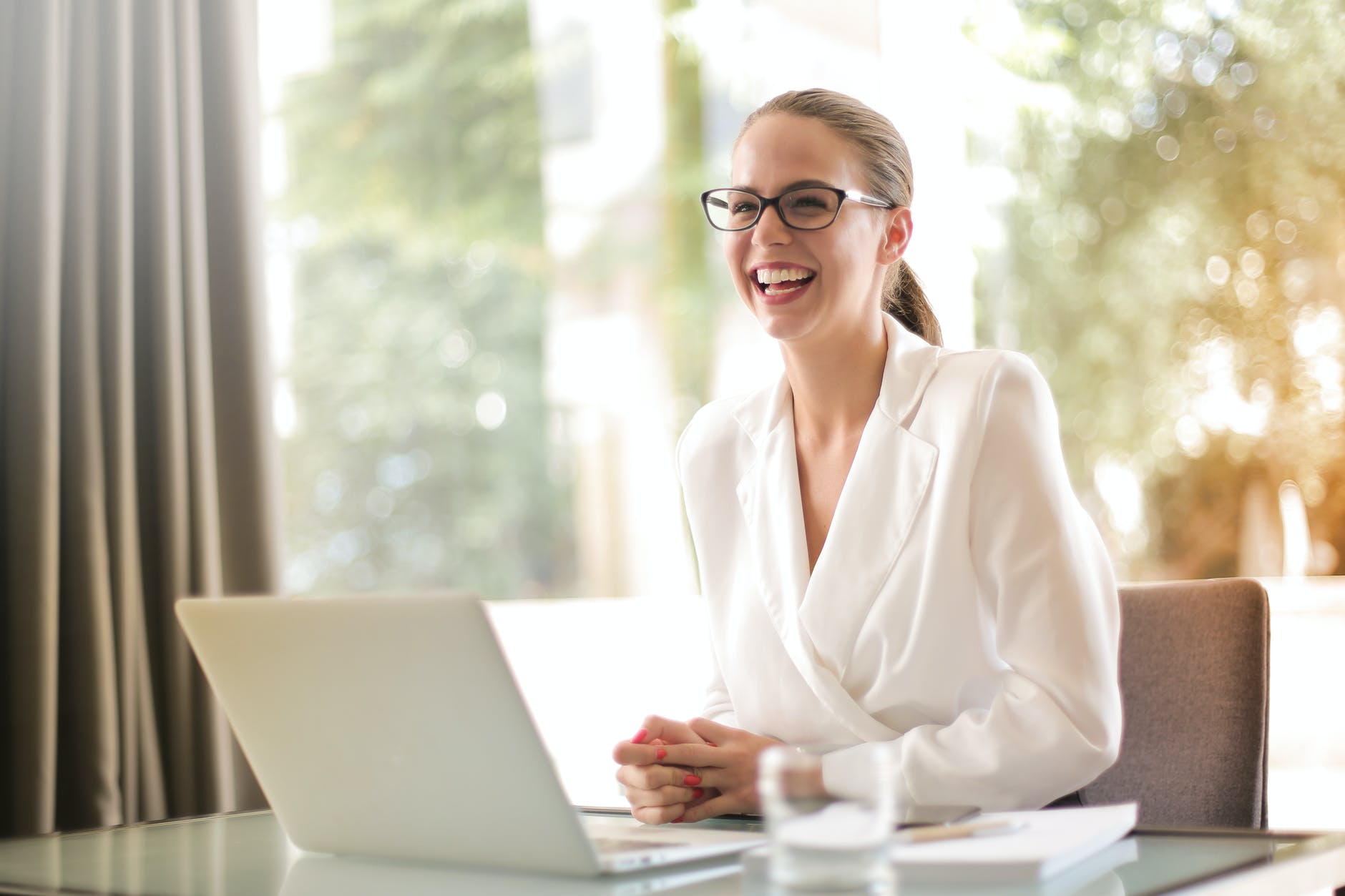 laughing businesswoman working in office with laptop ways to reward work from home employees
